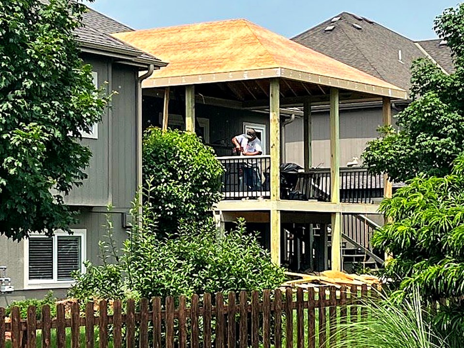 Sheathing and roofing being installed on the porch.